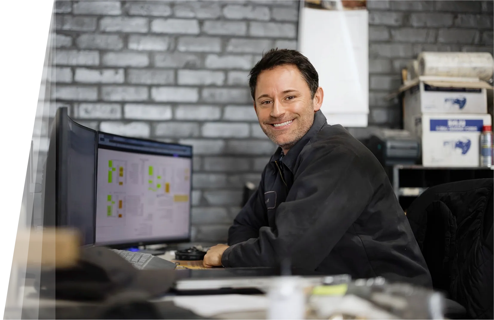 A service business owner smiling at their desk while working at a computer.