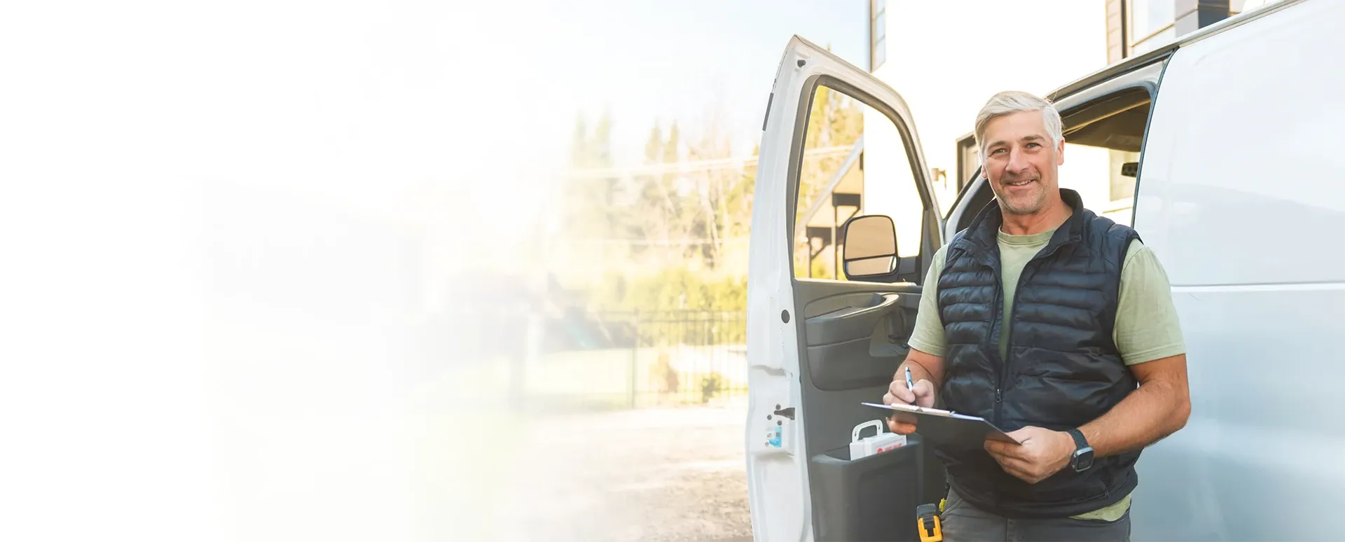 A service business owner standing beside their work van, reviewing paperwork.